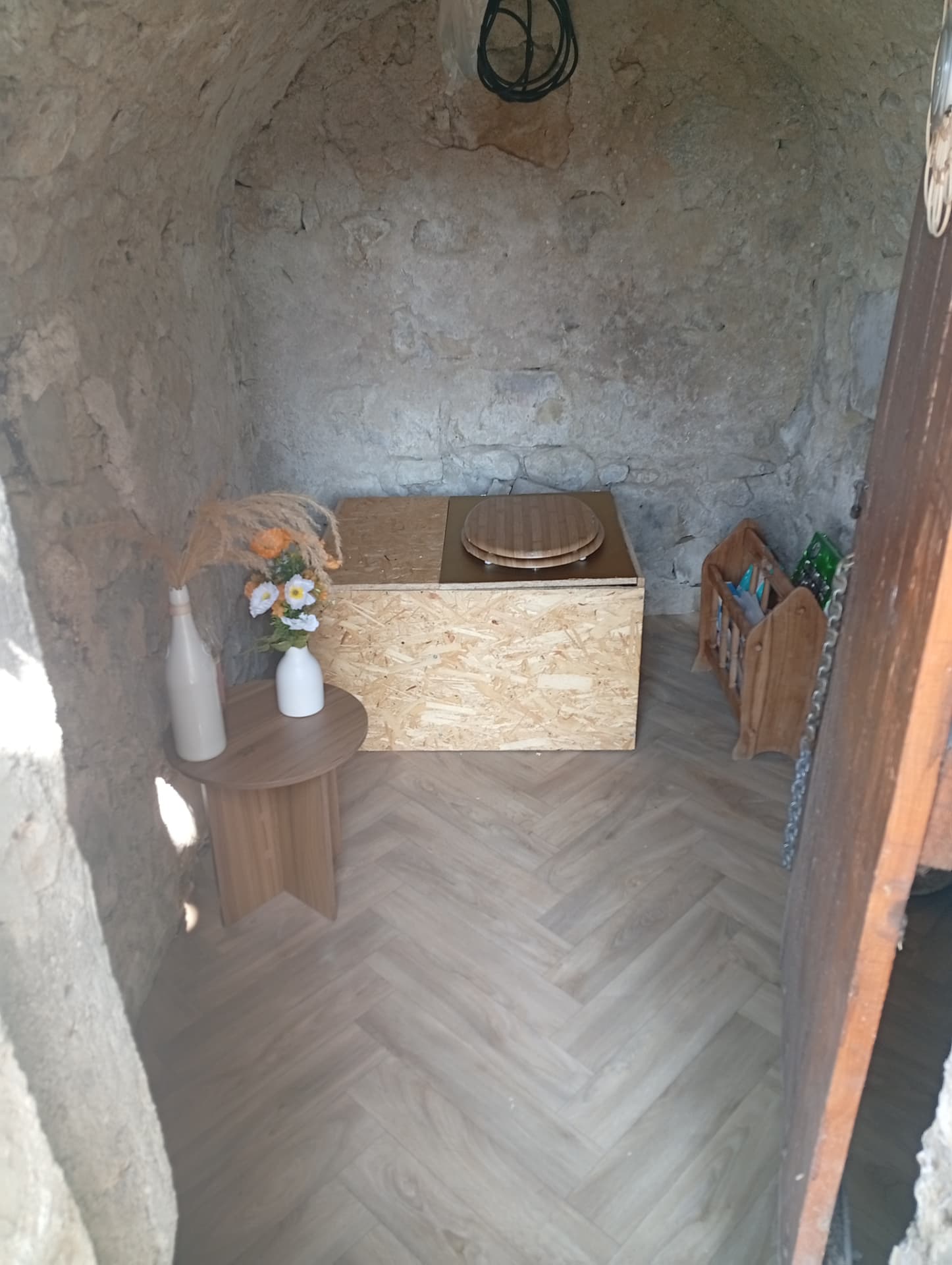 Toilette sèche en bois dans une cabane en pierre